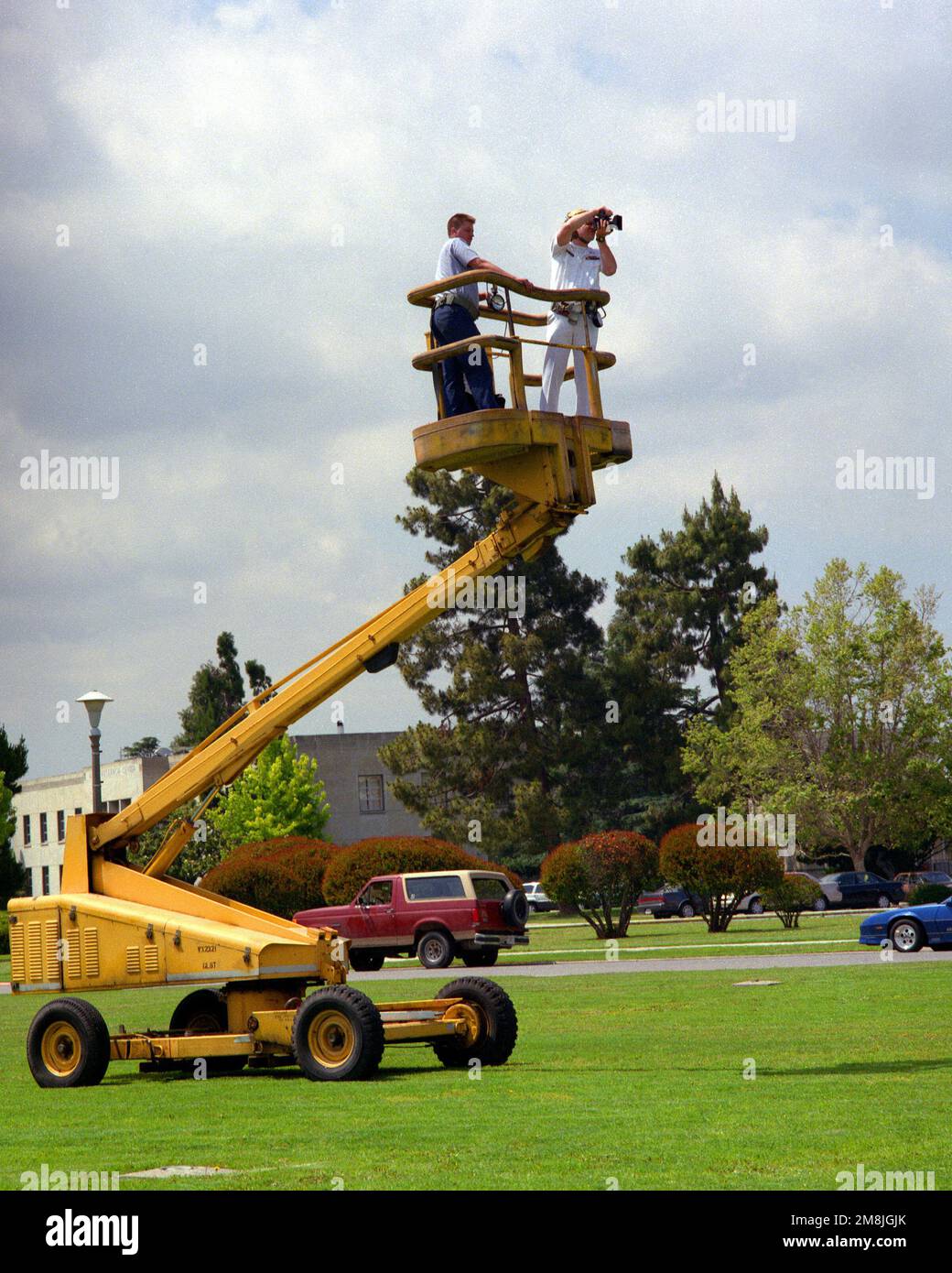Der Kamerad eines Fotografen verwendet einen Kirschpflücker als Plattform, um ein Gruppenfoto des verbleibenden aktiven Personals zu schießen, das der Naval Air Station Moffett Field vor der Disposition der Basis zugewiesen wurde. Basis: Sunnyvale Bundesstaat: Kalifornien (CA) Land: Vereinigte Staaten von Amerika (USA) Stockfoto