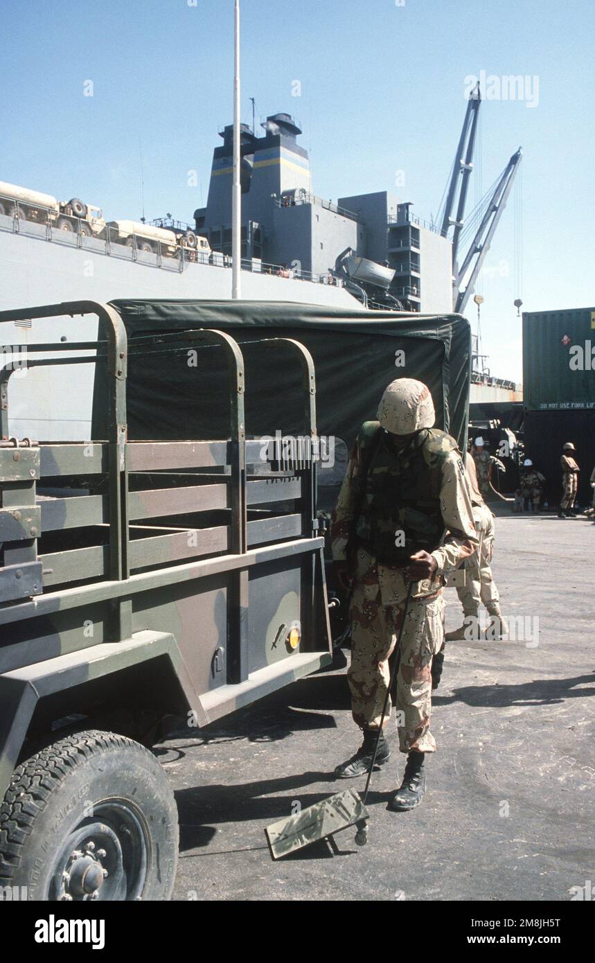 PFC Kevin Johnson, USA Die Armee der 155. Transportation Company, Fort Eustis, VA, verwendet einen Spiegel, um unter einem Fahrzeug zu prüfen, da er die Sicherheit bietet, bevor die Fahrzeuge in die USNS Denebola geladen werden. Einsatzgebiet/Serie: UNOSOM II Basis: Mogadischu Land: Somalia (SOM) Stockfoto