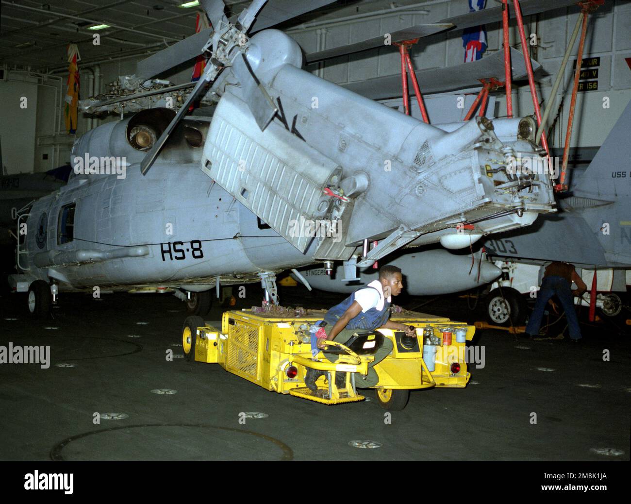 Der Traktorfahrer (AN) Donald Walker schleppt einen SH-60 Sea Hawk Hubschrauber der Helicopter Squadron 8 (HS-8) mit einem SD-1D-Spürhund über die Hangarbucht des nuklearbetriebenen Flugzeugträgers USS CARL VINSON (CVN-70). Land: Indischer Ozean (IOC) Stockfoto