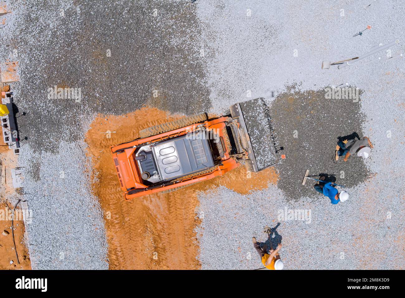 Auf der Baustelle wird ein Baggerlöffel verwendet, um Kies zu nivellieren, bevor Betongrundlagen des Gebäudes gegossen werden. Stockfoto