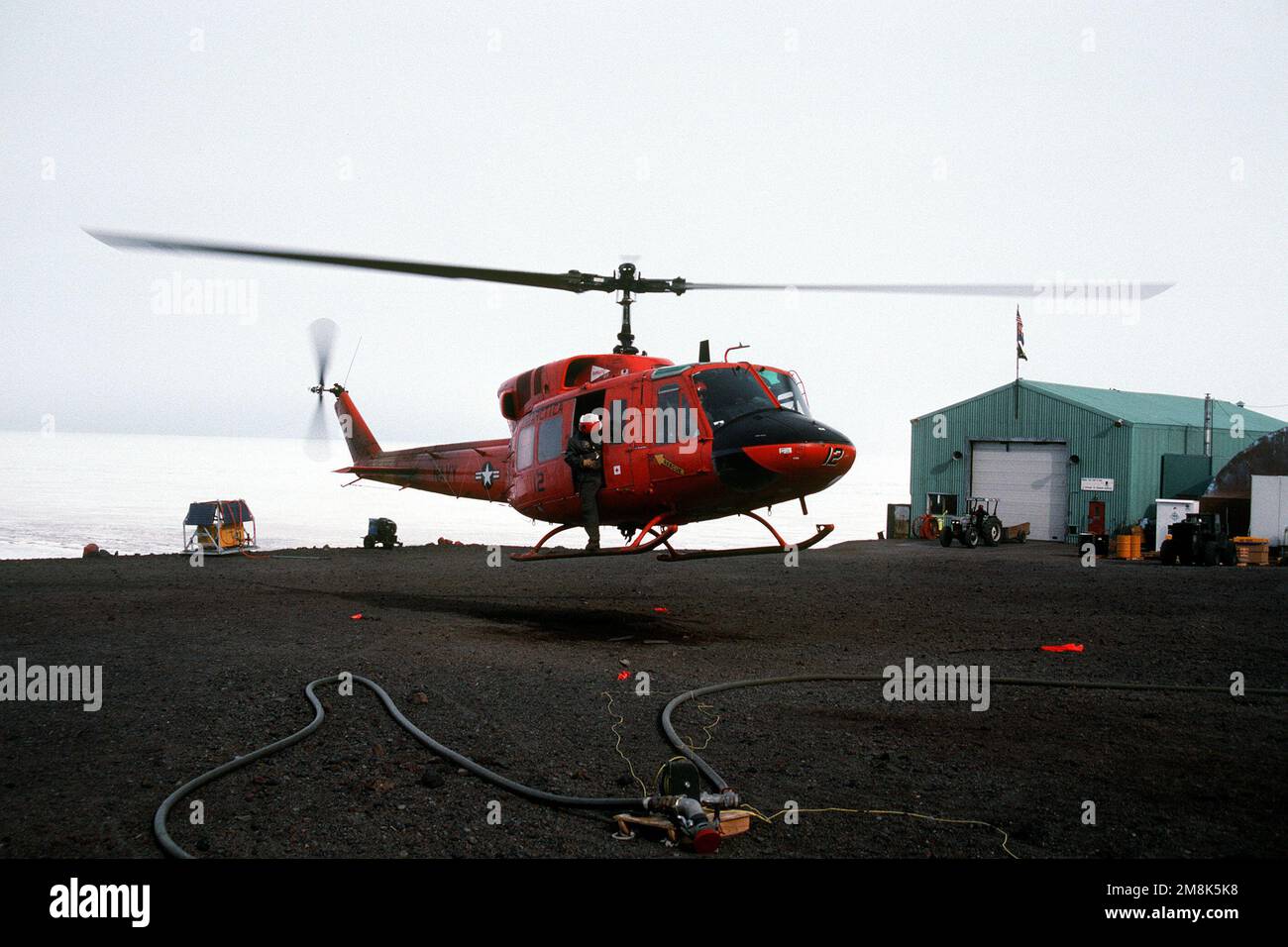 Air Crewman Aviation Machinist Mate Third Class (AD3) Tim Phillips überprüft den endgültigen Anflug von der Tür eines UH-1N sanften Helikopters AS LT. Greg Robinson landet auf dem McMurdo Sound helikopter. Staat: McMurdo Sound Country: Antarktis (ATA) Stockfoto