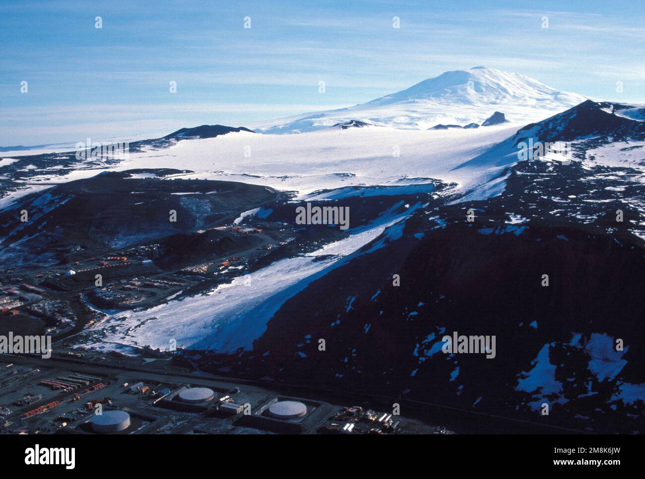 Ein Blick auf einen Teil der McMurdo Station aus Sicht des Observation Hill (Höhe 750 Fuß). Im Hintergrund befindet sich ein schneebedeckter Berggipfel. Staat: McMurdo Sound Country: Antarktis (ATA) Stockfoto