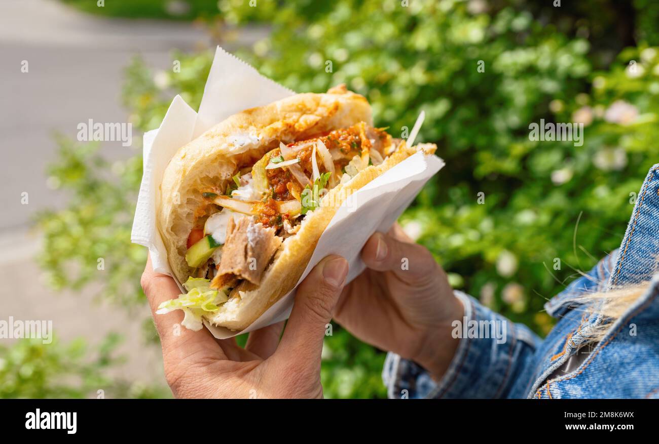 Frau mit einem Döner Kebab (Sandwich) in Deutschland, berühmter Kebab Fast Food Snack in Fladenbrot. Stockfoto