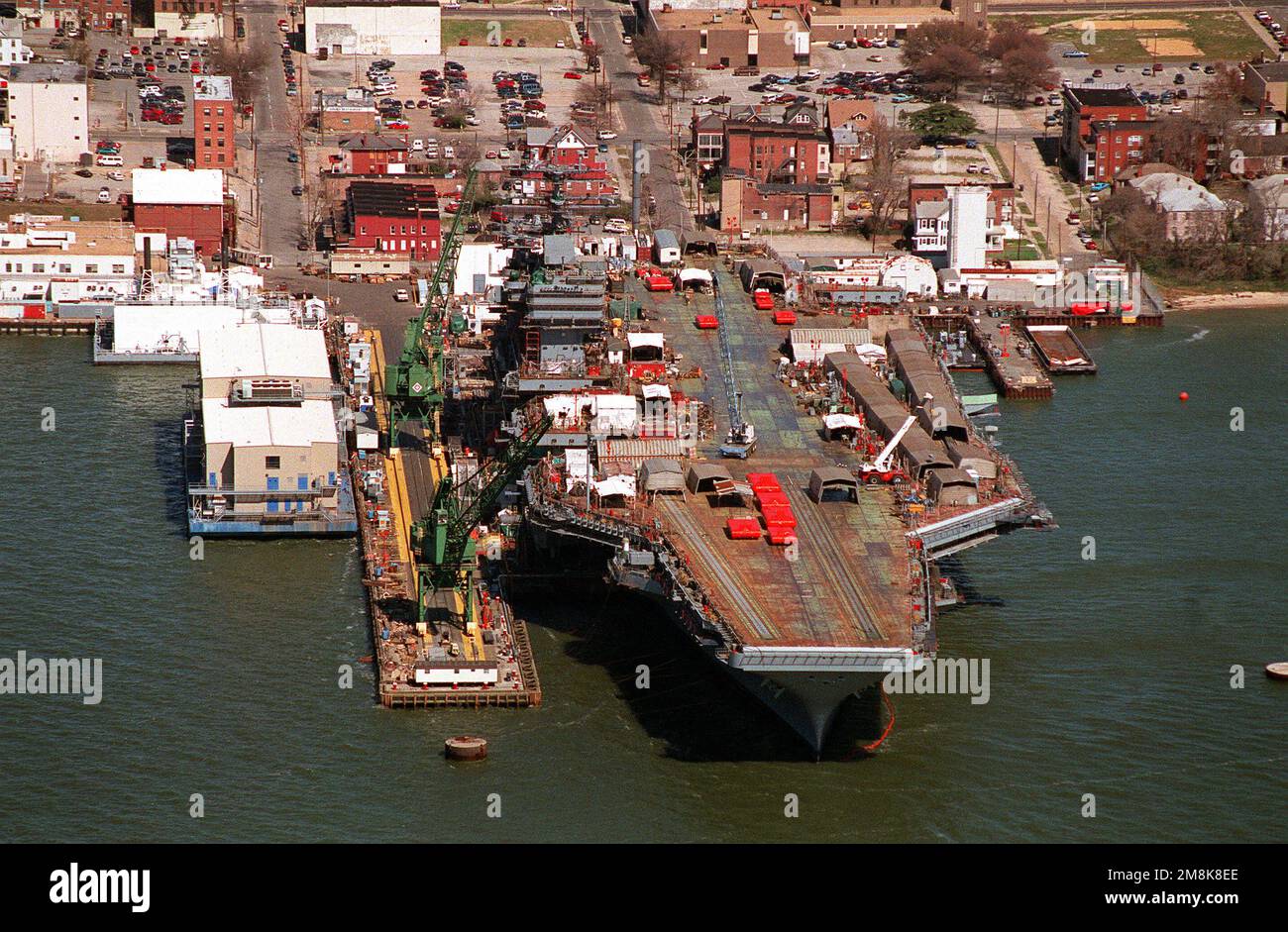 Ein Luftbogen zum nuklearbetriebenen Flugzeugträger JOHN C. STENNIS (CVN-74) am Fitting Pier bei Newport News Shipbuilding und Drydock Corporation am James River. Die orangefarbenen Dollies auf dem Deck sind Katapult-Testbänke und werden aus den Katapulten getestet, um das Gewicht des Flugzeugs zu simulieren. Basis: Newport News Bundesstaat: Virginia (VA) Land: Vereinigte Staaten von Amerika (USA) Stockfoto