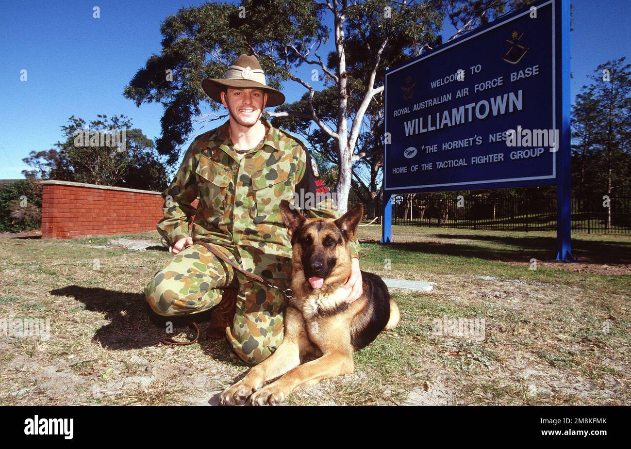 LAC Paul McNear und sein Polizeihund King von der Royal Australian Air Force (RAAF) Security Section posierten während der Iron Fist '95, einer Luftverteidigungsübung zwischen den USA, am Haupttor Air Force F-15s und RAAF F-18s von den Geschwadern 3 und 77. Betreff Operation/Serie: IRON FIST '95 Basis: RAAF Williamstown Land: Australien (AUS) Stockfoto