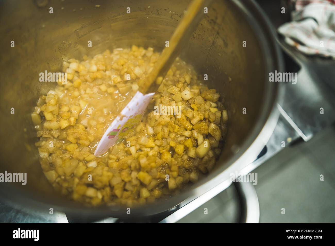 Mit einem Holzlöffel gehacktes Apfel- und Zimtpulver umrühren und Apfelkuchen zubereiten. Hochwertiges Foto Stockfoto