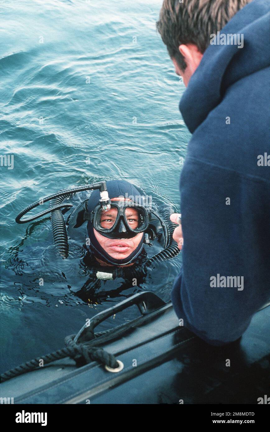 März 1992... Ein Taucher der Marine im Wasser erhält Anweisungen von einem Schiffskameraden an Bord eines kleinen Boots vor dem Strand der Amphibienbasis. Basis: Coronado Bundesstaat: Kalifornien (CA) Land: Vereinigte Staaten von Amerika (USA) Stockfoto