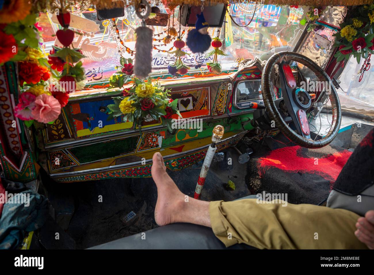 Fahrer schläft auf den Sitzen eines bunt bemalten Busses, Peshawar, Pakistan Stockfoto