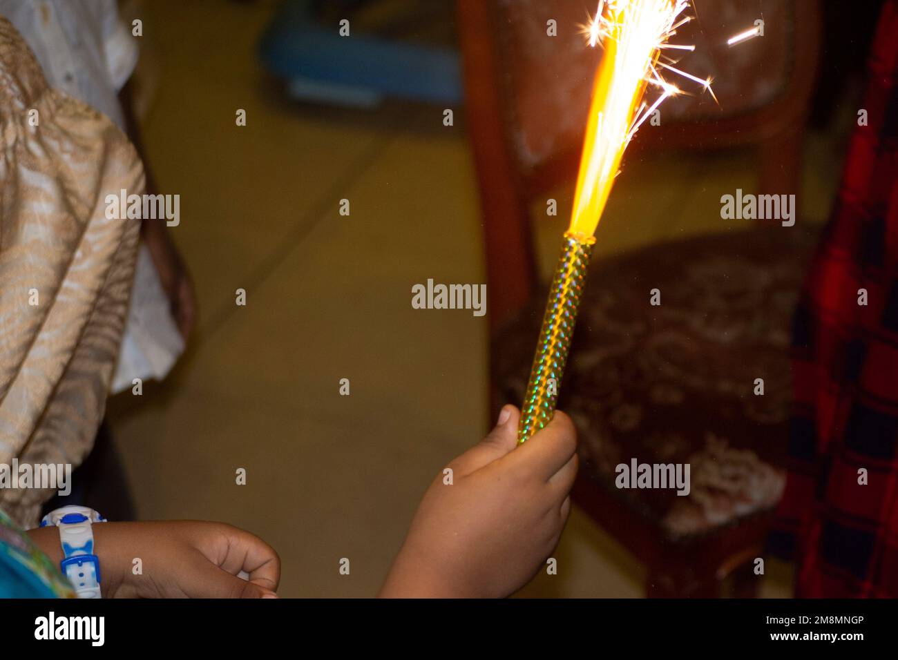 Die Hand eines Kindes hält ein brennendes Feuerwerk Stockfoto