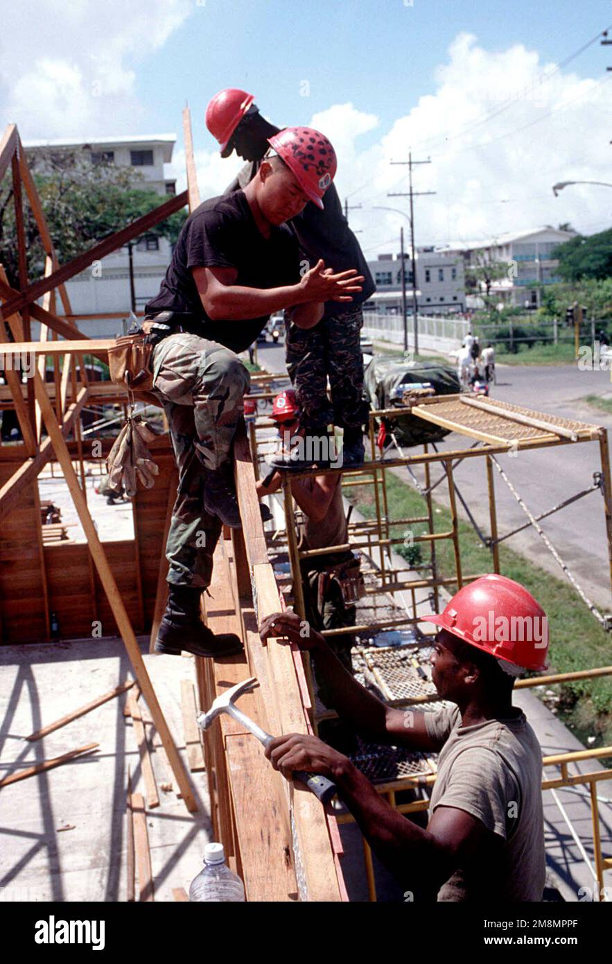 SENIOR AIRMAN Seth Mellott, 820. Rapid Engineer Deployable Heavy Operations Repair Squadron Engineering Squadron, Nellis Air Force Base, NV, weist den Lance Corporal Ebbionne Stevens der Guyana Defense Force an, wo die Dachverbindung am Rahmen des Gebäudes befestigt werden soll. Militärangehörige von Red Horse, USA Die Marine Corp und die Guyana Defense Force, die der Combined Task Force Falcon zugeteilt wurden, schlossen sich zusammen, um die St. Mary's High School im Rahmen der ersten kombinierten humanitären und zivilen Hilfsaktion zwischen den Vereinigten Staaten und Guyana wieder aufzubauen. Militärpersonal der Air Force, Ai Stockfoto