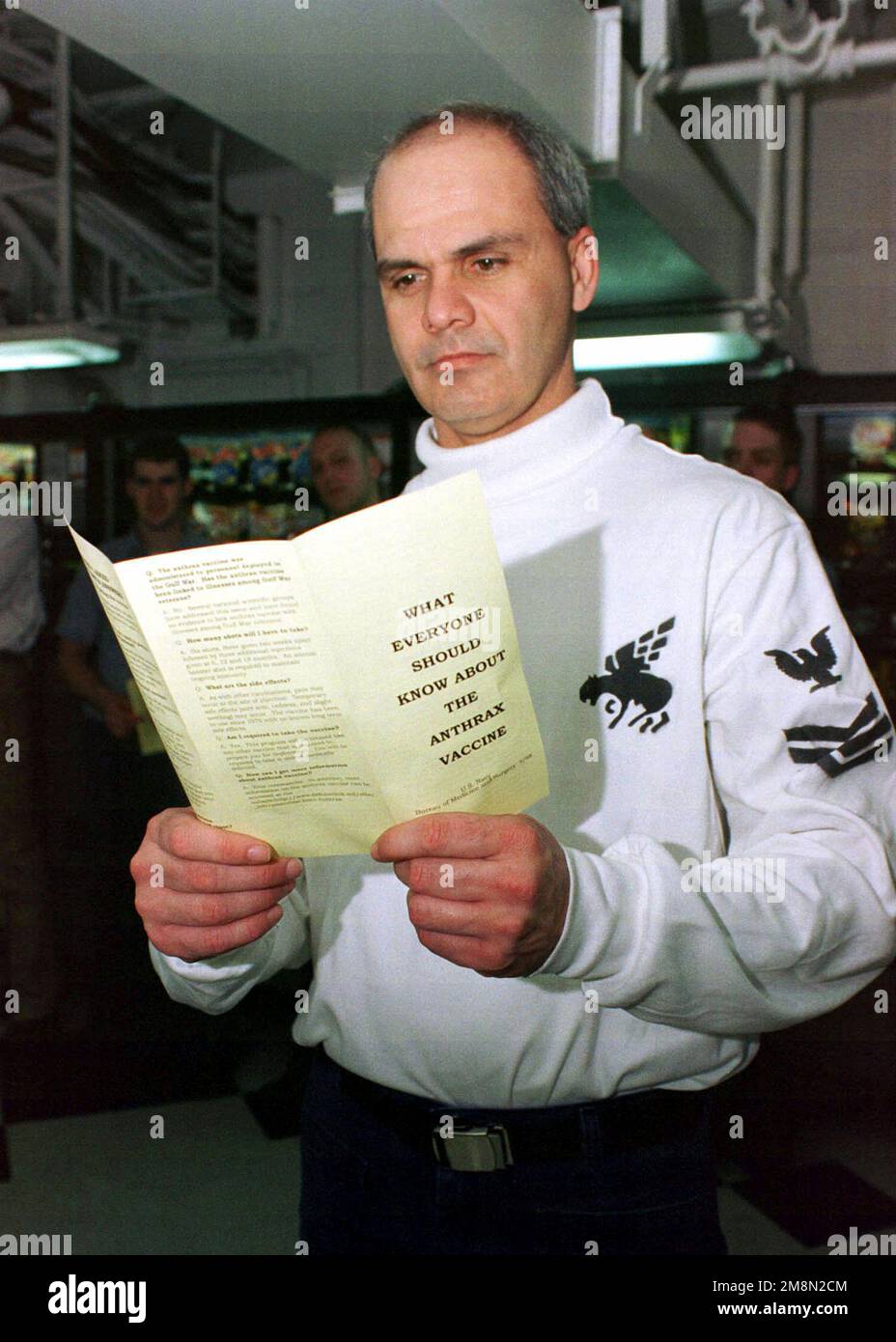 US Navy Aviation Structural Mechanic 1. Klasse David Snodgrass, von VF-143, liest ein Navy-Pamphlet über den Anthrax-Impfstoff, während sie in der Schlange warten, um die ersten in einer Reihe von Anthrax-Impfungen an Bord des Nimitz Class Aircraft Carrier, USS JOHN C. STENNIS (CVN 74) zu erhalten. Die STENNIS werden im Persischen Golf eingesetzt, um die Operation Southern Watch zu unterstützen. Betreff Betrieb/Serie: SÜDLICHE WACHSTATION: USS John C. Stennis (CVN 74) Stockfoto