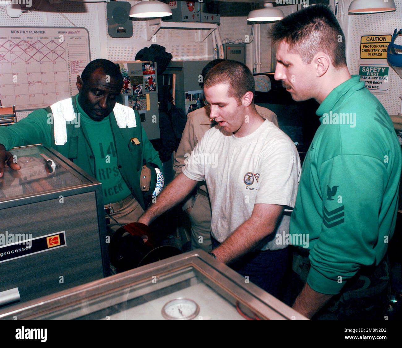 An Bord des Flugzeugträgers der Nimitz-Klasse bewerten USS JOHN C. STENNIS (CVN-74), (links-rechts) US Navy CHIEF Warrant Officer Ernie Kimbrough, der AIRMAN des Fotografen Richard Brunson und Mate First Class Scott Shields den Luftfilm einer Mission von einem EH-38-Filmprozessor. Die USS JOHN C. STENNIS wird im Persischen Golf eingesetzt, um den Aufbau Südwestasiens zu unterstützen. (Offiziell veröffentlicht von COMFIFTHFLT Public Affairs). Basis: USS John C. Stennis (CVN 74) Stockfoto