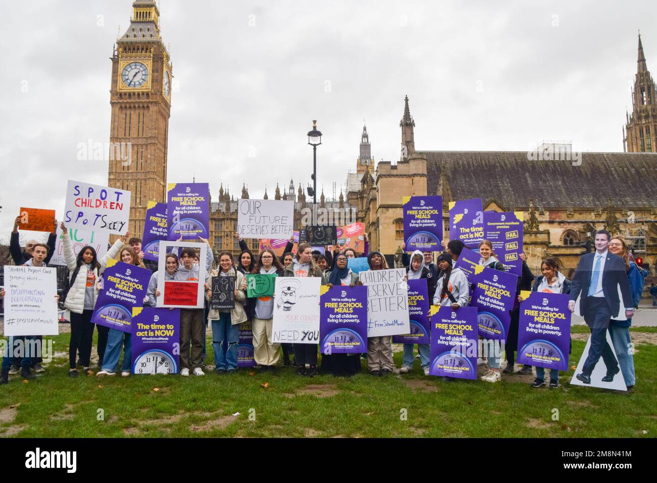 London, Großbritannien. 14. Januar 2023. Die Schüler halten während der Rallye am Parliament Square Plakate für kostenlose Schulmahlzeiten und einen Pappausschnitt von Jeremy Hunt. Schulkinder versammelten sich in Westminster zu einer Kundgebung, inszeniert von der gemeinnützigen Organisation Bite Back 2030, die Jeremy Hunt, den Schatzkanzler, aufforderte, allen in Armut lebenden Kindern kostenlose Schulmahlzeiten zur Verfügung zu stellen. Die Organisation reichte dann eine Petition an die Downing Street 10 ein, die von über 250.000 Personen unterzeichnet wurde. Kredit: SOPA Images Limited/Alamy Live News Stockfoto