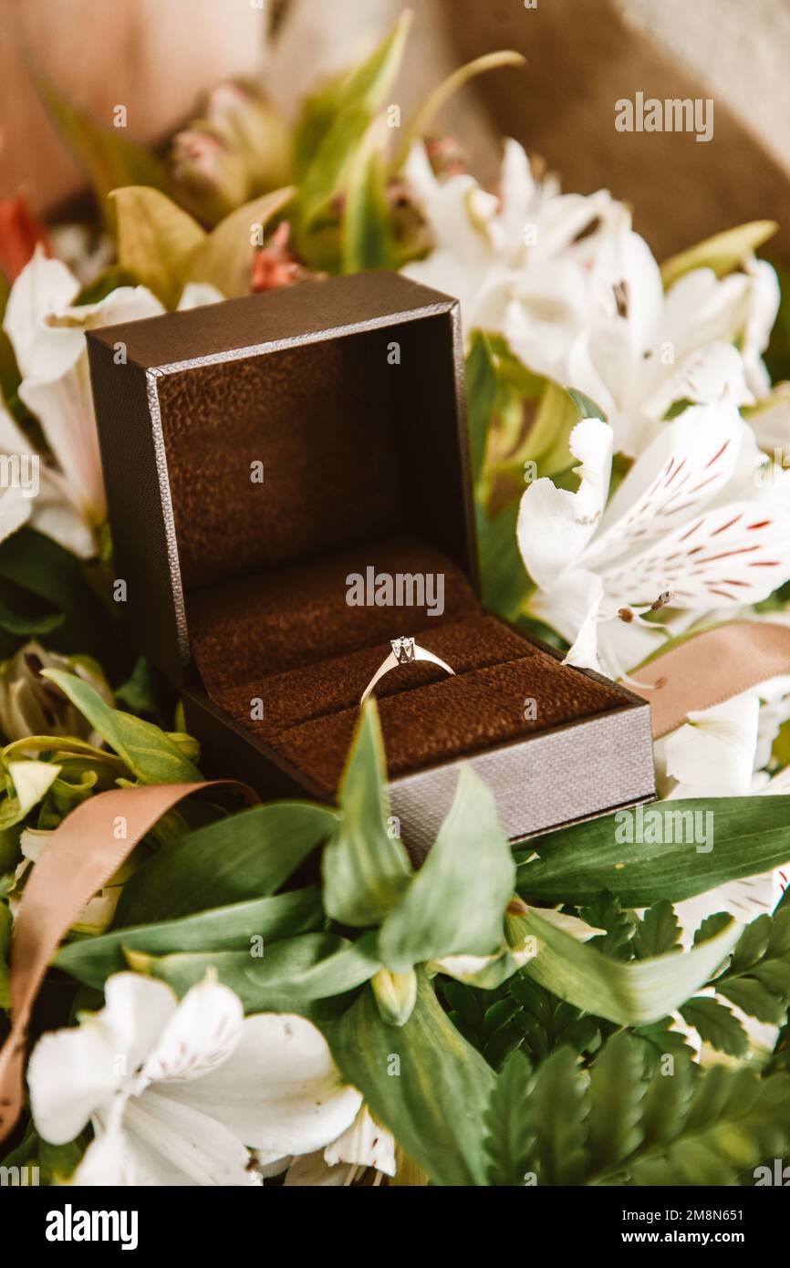 Ehering in einer Schachtel Nahaufnahme, Goldring mit einem Diamanten in Blumen. Hochzeit, 14. Februar, Valentinstag, Heiratsantrag für die Braut, Schmuck. Stockfoto