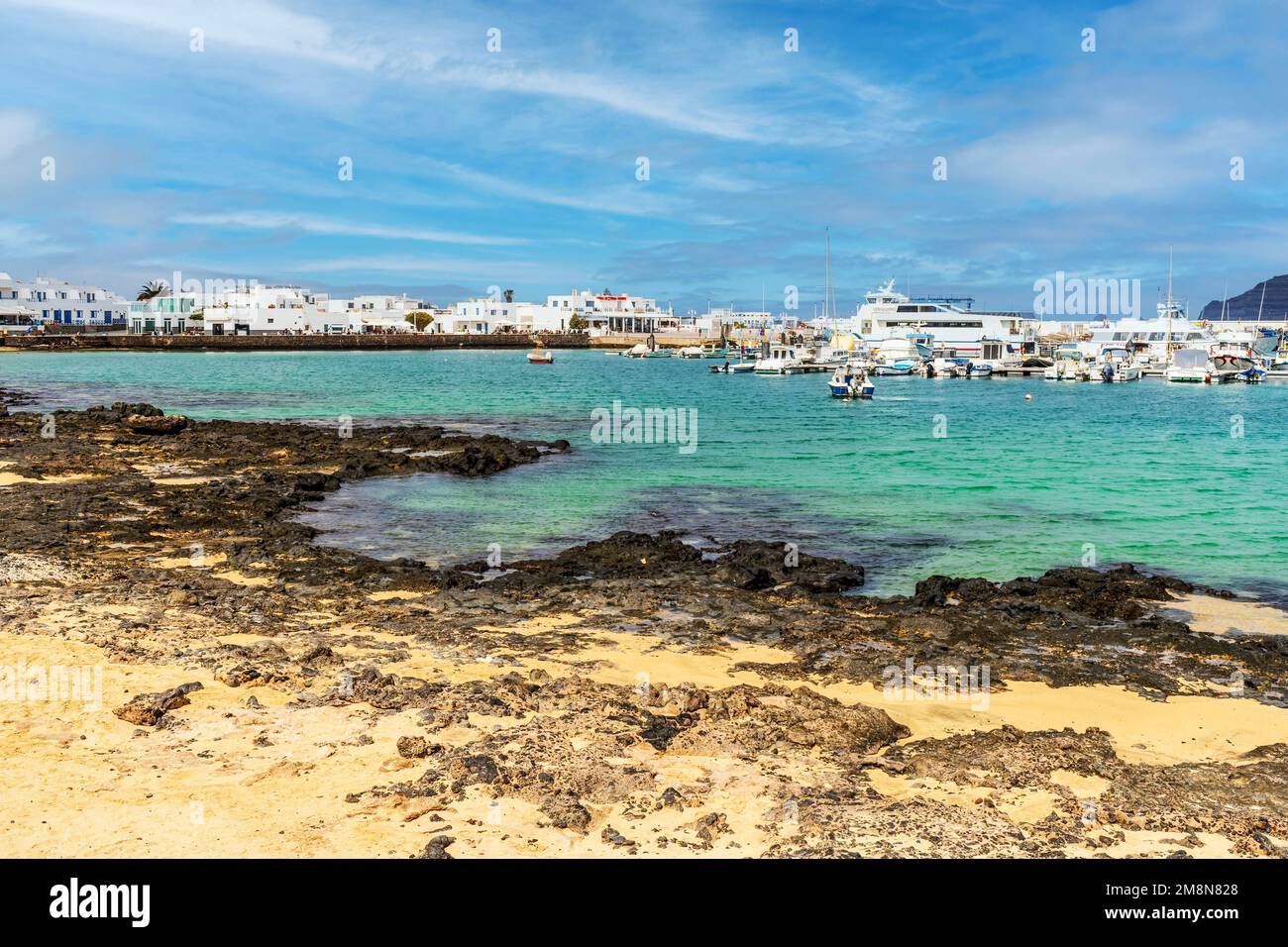 Strand und Hafen mit Booten und Fähren in Caleta del Sebo, La Graciosa ...