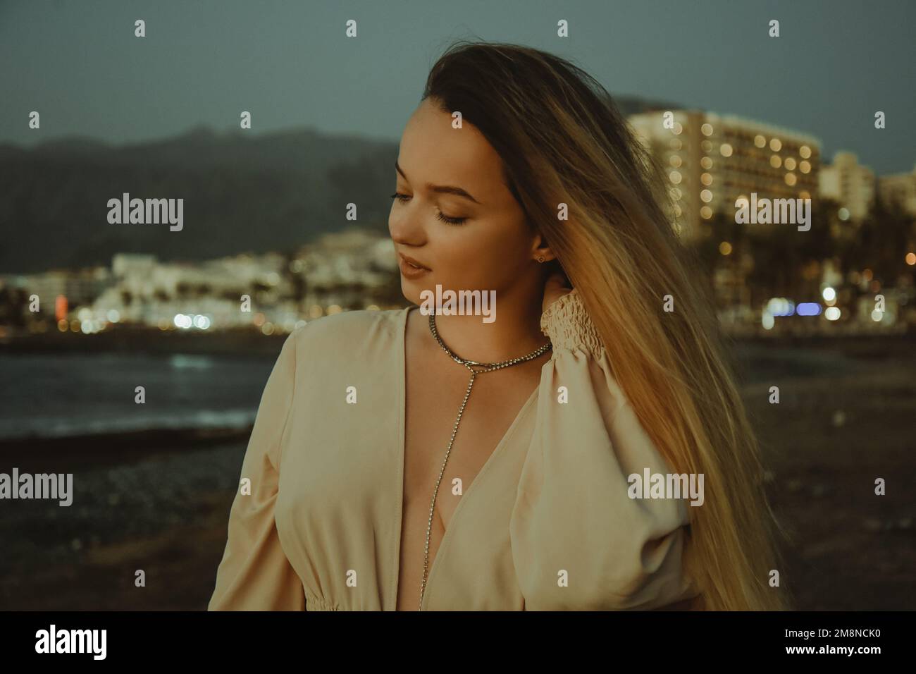 Ein wunderschönes Mädchen in einem Kleid und Schmuck im Hintergrund des Sonnenuntergangs im Hintergrund des Meeres, eine Frau mit langen Haaren auf einem Urlaubsporträt, Palm t Stockfoto