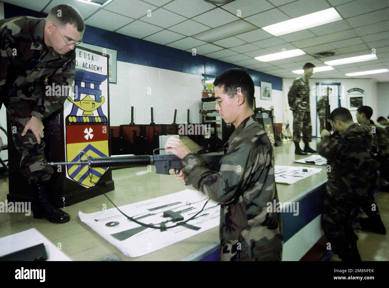 SSGT Steven Humes, Platoon-Dozent am koreanischen Trainingscenter der US Army (KATUSA), Camp Jackson, Republik Korea, evaluiert einen Trainee für die Ausräumung eines M-16 am 30. Oktober 1998. Das ursprünglich 1950 aufgelegte KATUSA-Programm wurde entwickelt, um die US-Streitkräfte unmittelbar nach dem Ausbruch des Koreakrieges zu verstärken. Nach dem Waffenstillstand blieben KATUSA-Soldaten bei 8. Armeeeinheiten, um die Einsatzfähigkeit zu verbessern. Koreanische Enlistees nehmen an einem 20-tägigen Trainingsprogramm im Zentrum Teil, wo sie ihre Englischkenntnisse verbessern und mehr über die amerikanische Kultur und die Struktur der US-Armee erfahren Stockfoto