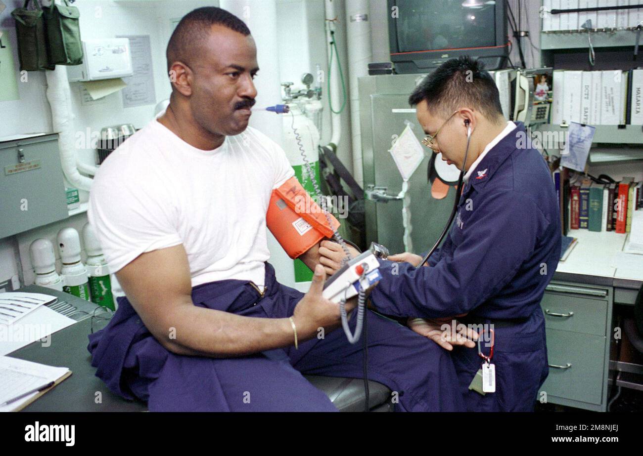 US Navy Store Keeper erste Klasse Leo Suber hat seine Vitalzeichen in der medizinischen Praxis an Bord der USS NICHOLAS (FFG 47) von US Navy Hospital Corpsman dritte Klasse Stephen Albright aufgenommen. Nicholas ist vorwärts in die Adria einmarschiert. Basis: USS Nicholas (FFG 47) Land: Auf See Stockfoto