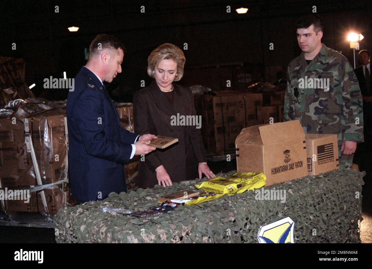 Direkt auf dem mittleren Bild von US First Lady Hillary Rodham-Clinton als USAF Colonel Felix Grieder, Commander 436. Airlift Wing, Dover Air Force Base, Delaware, zeigt ihr, wie die humanitären Hilfsmahlzeiten, fertig zum Essen (MRE), verpackt werden, bevor sie verarbeitet und an die Kosovo-Flüchtlinge versandt werden (Flüchtlinge nicht abgebildet). Basis: Luftwaffenstützpunkt Dover Bundesstaat: Delaware (DE) Land: Vereinigte Staaten von Amerika (USA) Stockfoto