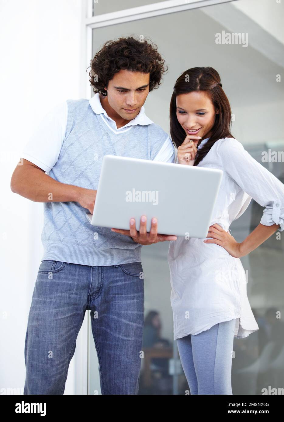 Dynamisches Duo, das einen Plan formuliert. Zwei junge Unternehmer, die zusammen an einem Laptop arbeiten. Stockfoto