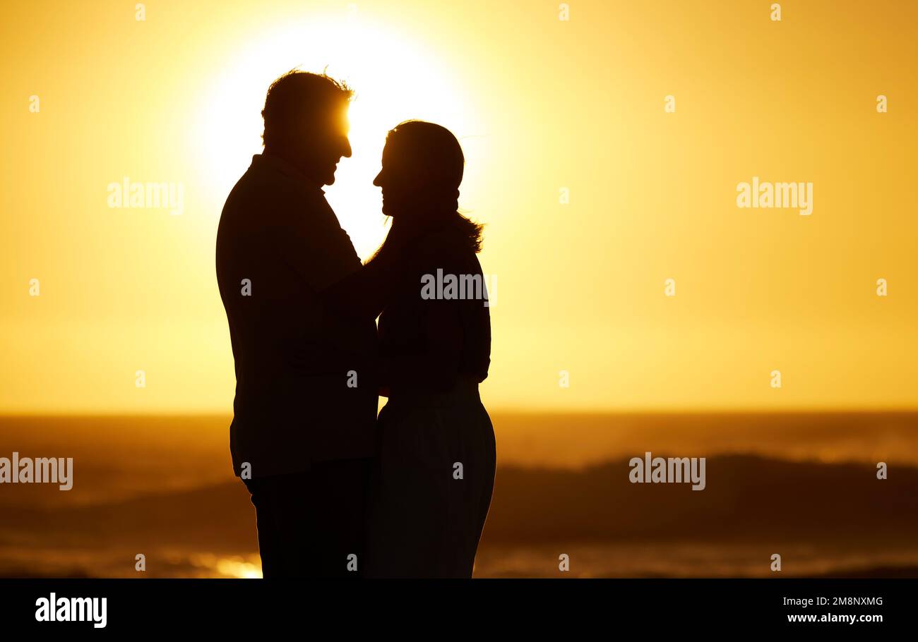 Die Silhouette des reifen Ehepaares im Urlaub. Seniorenpaar, das bei Sonnenuntergang am Strand in der Nähe ist. Verheiratetes Paar, das im Urlaub liebevoll ist Stockfoto