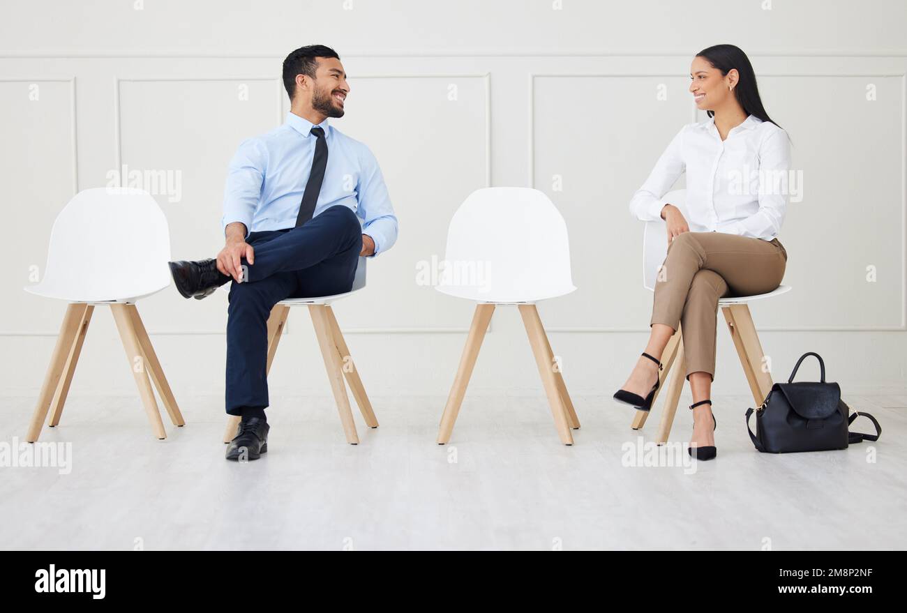 Zwei Geschäftsleute unterhielten sich, während sie auf das Interview warteten. Lächelnder asiatischer Geschäftsmann und gemischte Geschäftsfrau, die soziale Distanz hält. Kandidat ist da Stockfoto