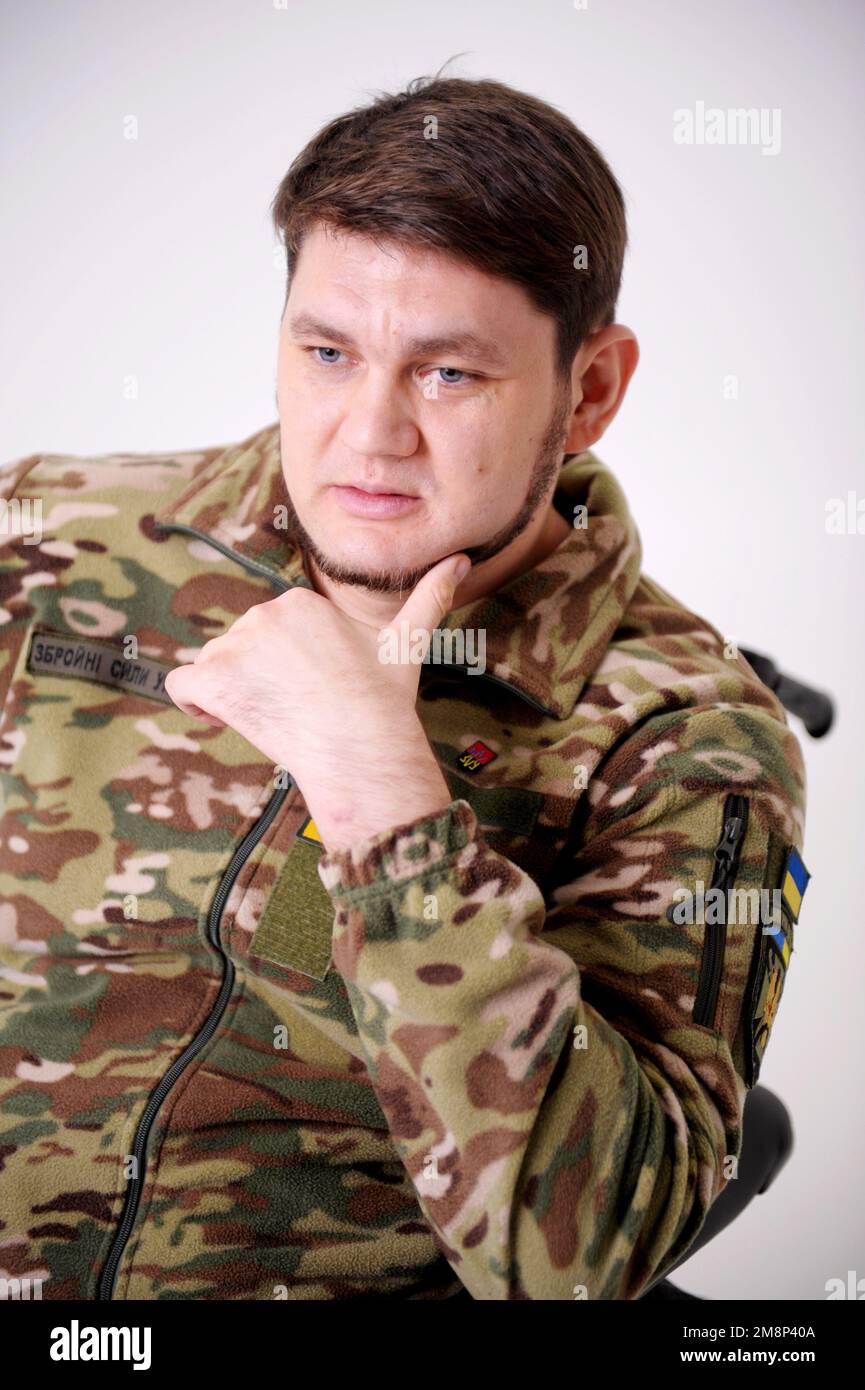 35 Jahre alter, attraktiver Mann des Militärs in Uniform, sitzt und raucht Er hat Ringe an den Fingern Emblem der Ukraine die ukrainische Flagge ist auf Schutzjacke genäht Geschichte der Ukraine Stockfoto