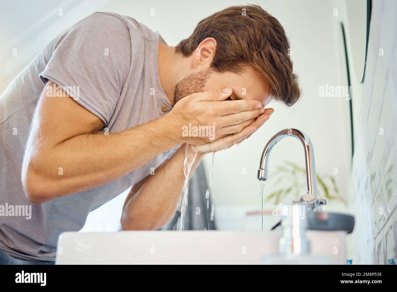 Ein hübscher Mann, der sein Gesicht in einem Badezimmer zu Hause wäscht. Kaukasischer Mann, der eine Gesichtswäsche verwendet, um Ausbruch, Akne und Hautunreinheiten in seiner Wohnung zu verhindern Stockfoto