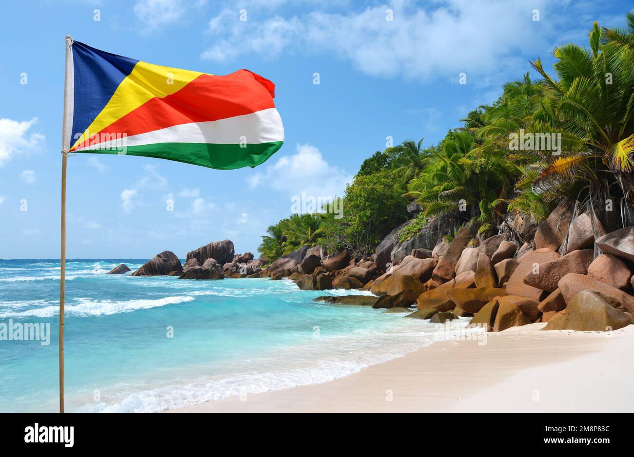 Anse Cocos Strand mit Seychellen-Flagge auf La Digue Island, Indischer Ozean. Tropische Landschaft mit sonnigem Himmel. Exotisches Reiseziel. Stockfoto
