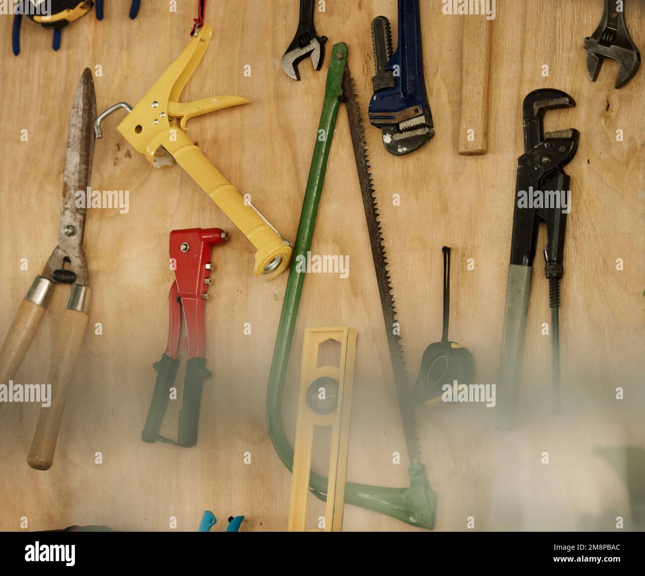 Eine Anordnung von Werkzeugen an einer Holzwand. Nahaufnahme einer Sammlung hängender Werkzeuge. Saubere, ordentliche Mechanikwerkzeuge und -Geräte an einer Wand. Stillleben von Stockfoto
