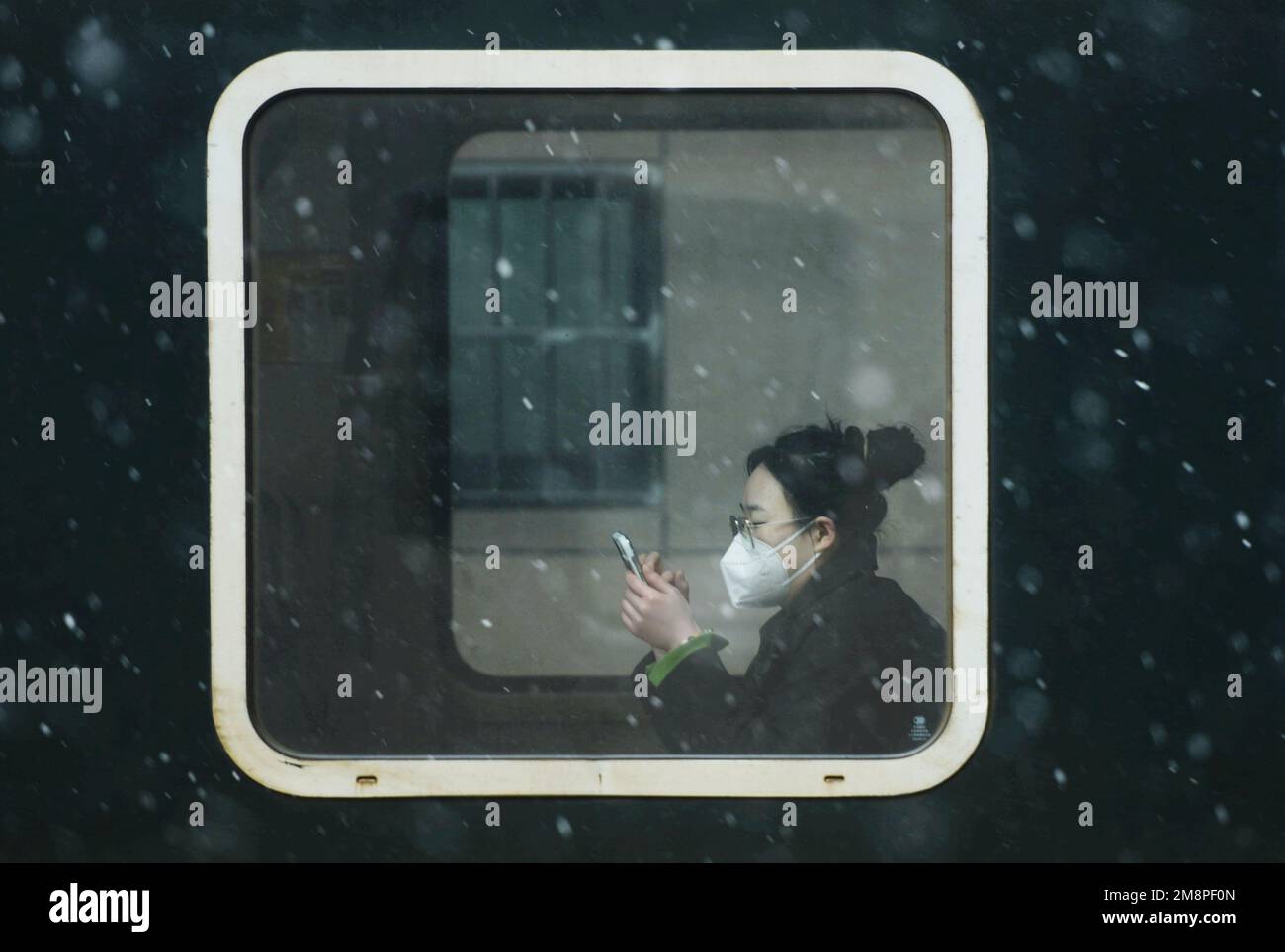 HANGZHOU, CHINA - 15. JANUAR 2023 - Schnee fällt vor einem Passagierzug, der am Bahnhof Hangzhou vorbeifährt, während die Passagiere auf die Heimfahrt warten Stockfoto