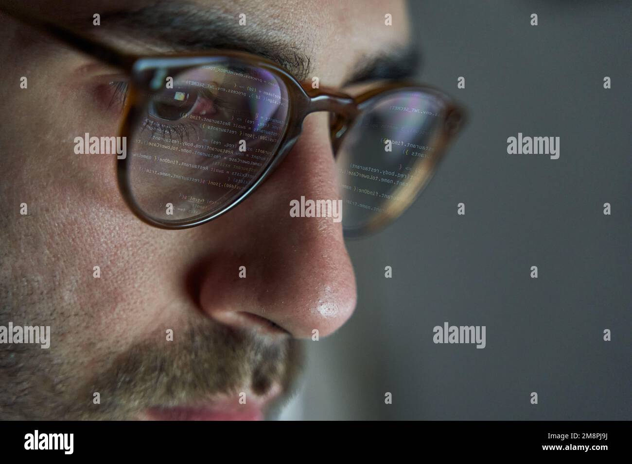Programmierer arbeitet an Code. Codezeilen werden in Brillen reflektiert. Entwicklung von Software und Website Stockfoto