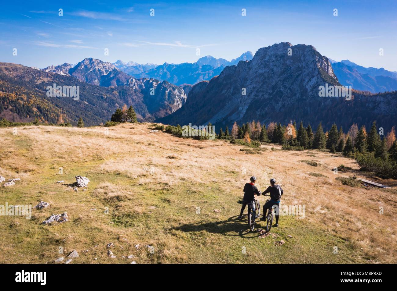 Mountainbiking in den österreichischen Alpen. Silhuette von Mountainbikern, die am späten Nachmittag im Herbst die malerische Aussicht auf Nassfeld genießen. Stockfoto