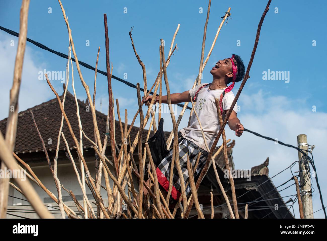 Bali, Indonesien. 14. Januar 2023. Ein Mann reagiert, nachdem er während der Feier des Kuningan Day im Dorf Munggu in Bali, Indonesien, am 14. Januar 2023 auf Holzstäbe geklettert ist, die in der Mekotek-Tradition in Pyramidenform zusammengefügt wurden. Kredit: Dicky Bisinglasi/Xinhua/Alamy Live News Stockfoto