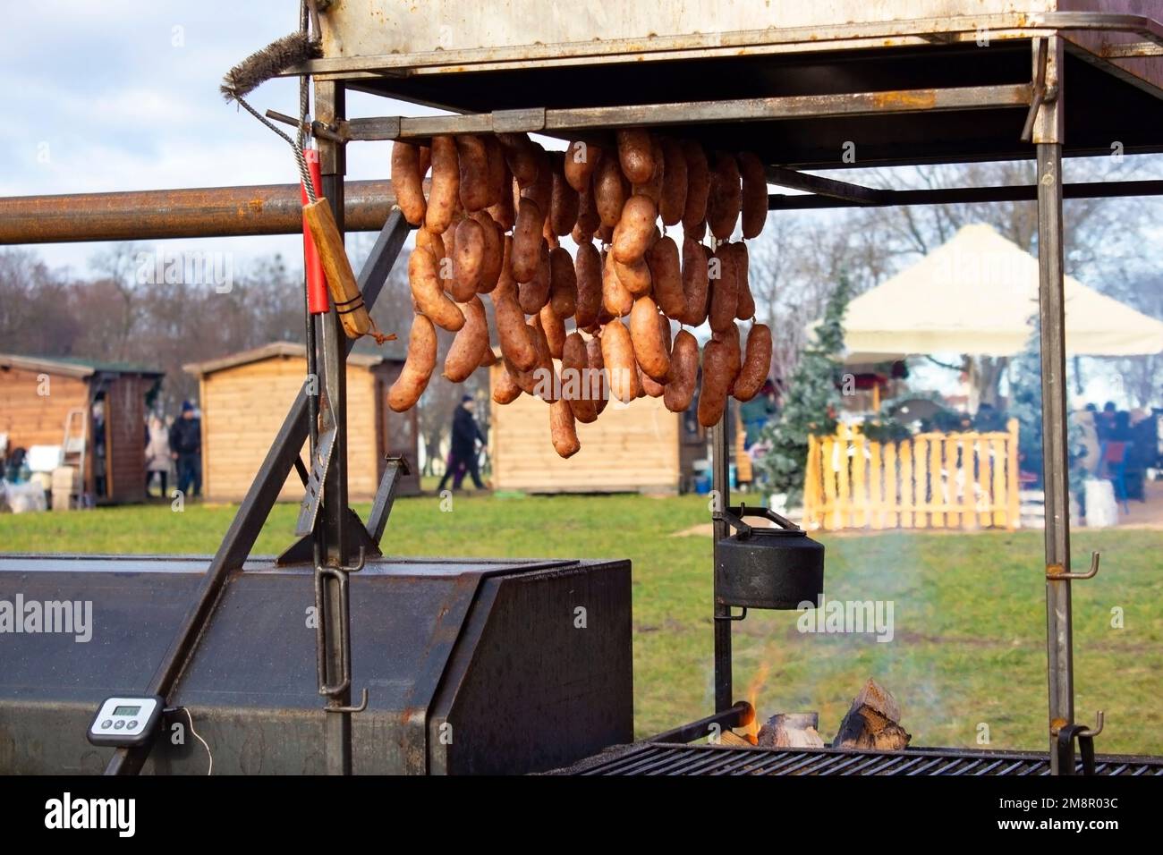 Köstliche heiße Würstchen, die in einem Metallofen gekocht werden, hängen auf dem Lebensmittelmarkt, traditionelle Fleischprodukte. Street Food Market. Stockfoto