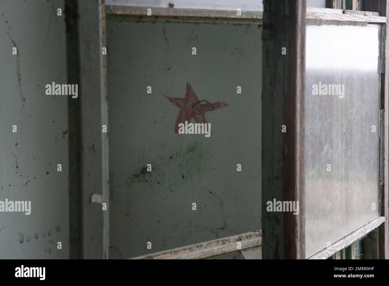 Roter Stern als Symbol des Kommunismus an der Wand in dem abgerissenen verlassenen Gebäude Stockfoto