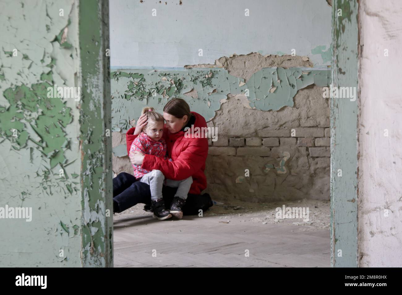 Mutter und Tochter in zerstörtem Gebäude. Krieg, Flüchtlinge, Kriegskrisenkonzept. Stockfoto