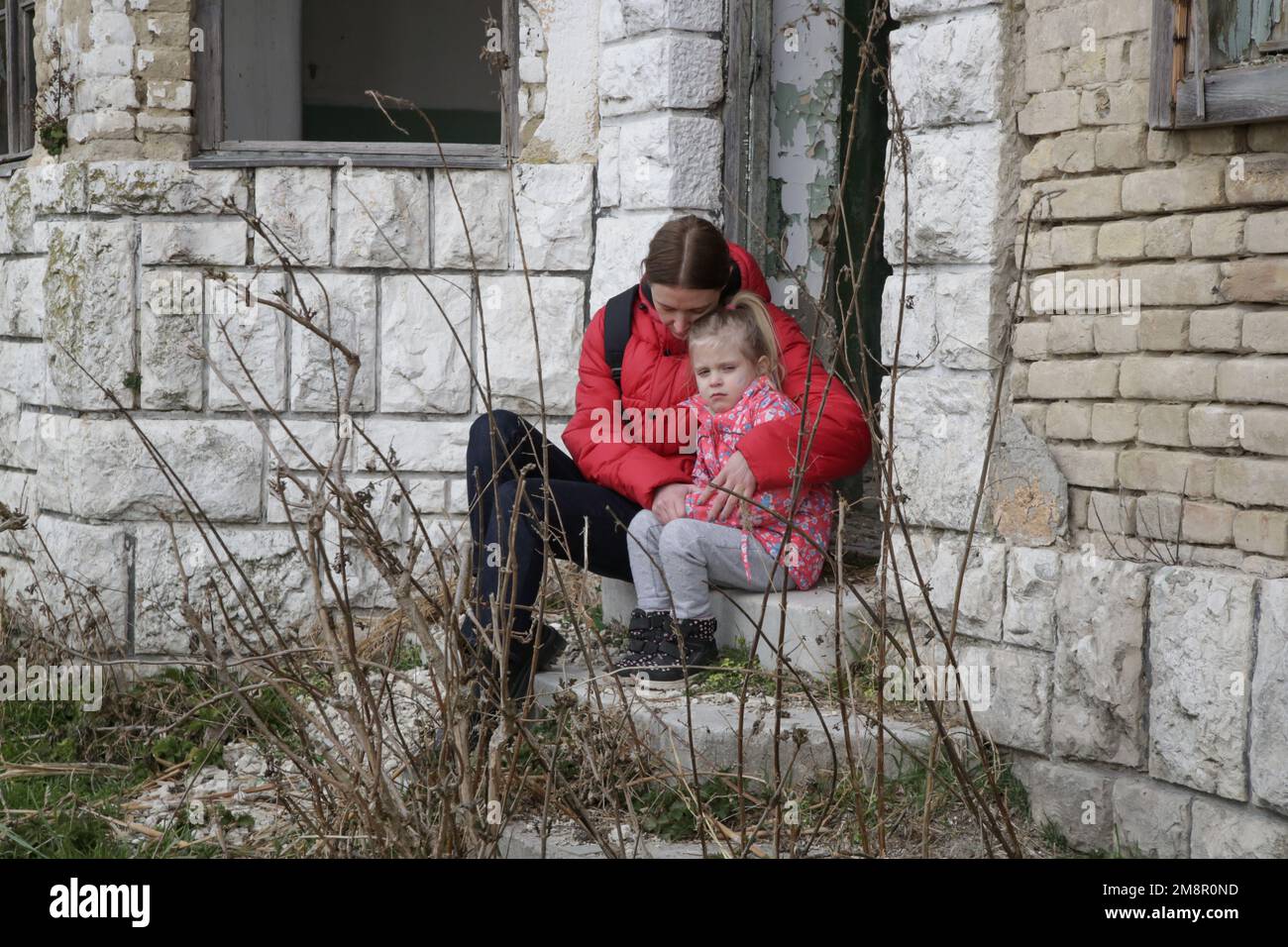 Mutter und Tochter in zerstörtem Gebäude. Krieg, Flüchtlinge, Kriegskrisenkonzept. Stockfoto