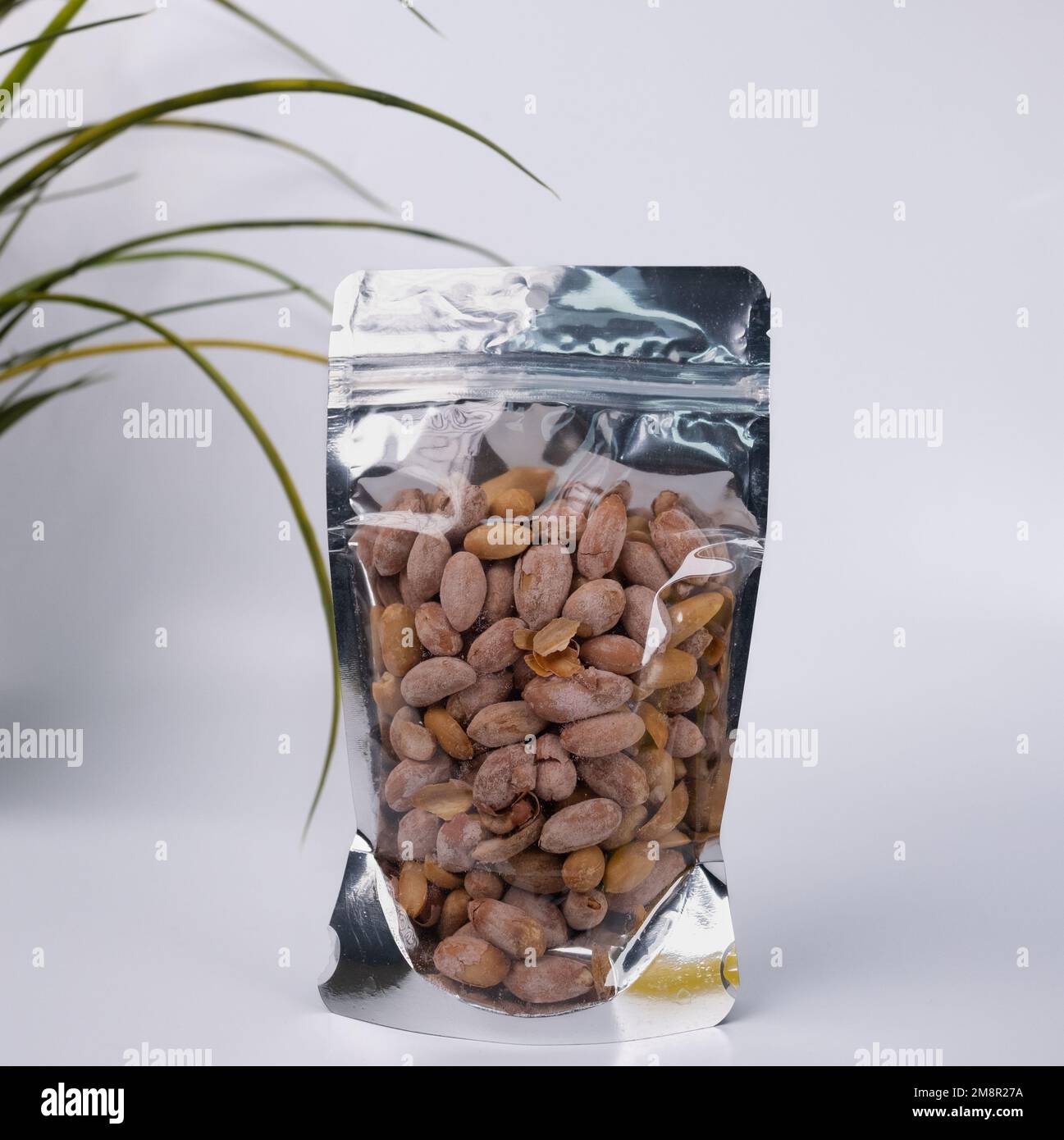 Erdnüsse in Kunststoffverpackung auf weißem Hintergrund. Stockfoto