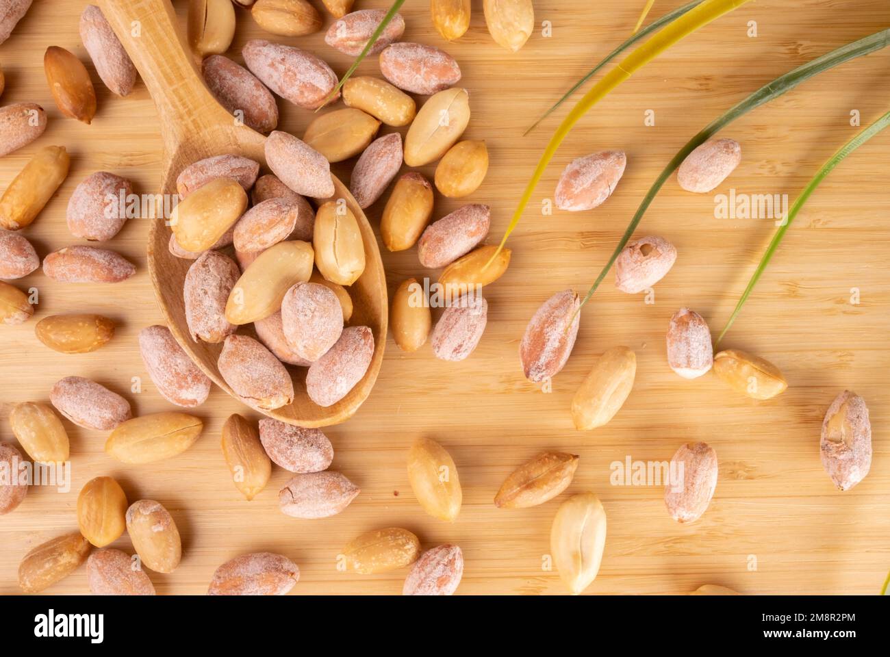 Erdnüsse in Holzlöffel auf Holzhintergrund. Ausgelaufene Gesalzene Erdnüsse Auf Holzhintergrund. Stockfoto