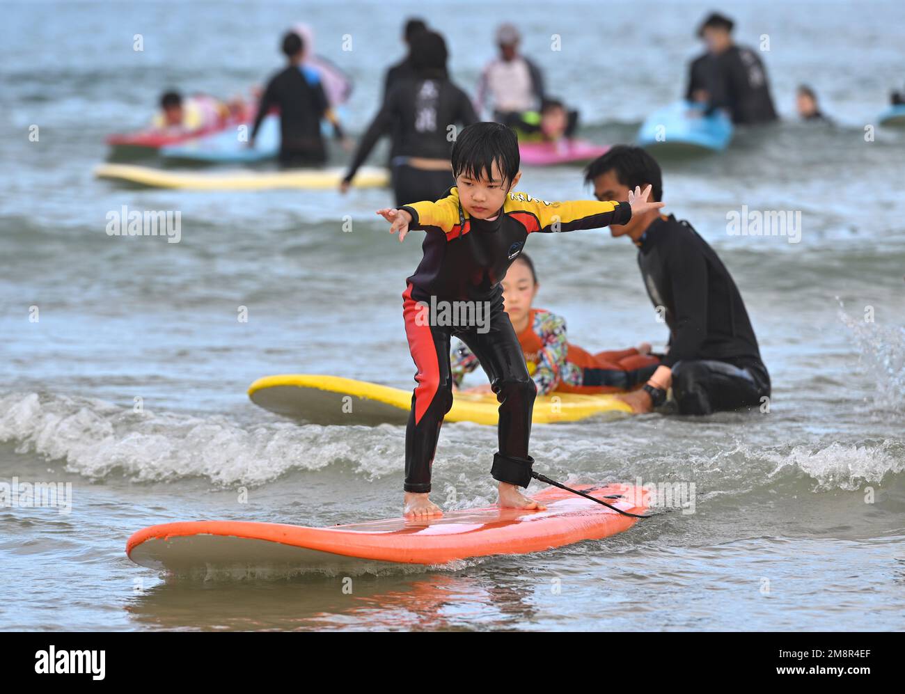 Wanning, Chinas Provinz Hainan. 13. Januar 2023. Ein Kind surft in der Riyue Bay in Wanning, südchinesische Provinz Hainan, 13. Januar 2023. Surfen ist dank seiner einzigartigen geografischen und klimatischen Vorteile zu einem Symbol von Wanning geworden. Kredit: Guo Cheng/Xinhua/Alamy Live News Stockfoto