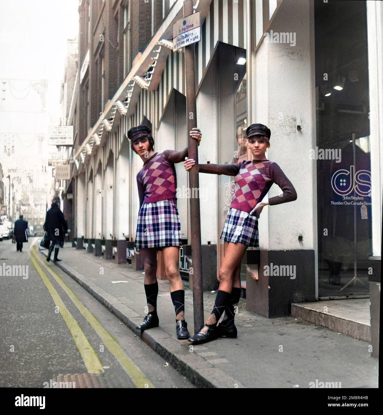 Ein Mann und eine Frau, die sich in identischen Outfits aus Pullover und Rock in der modischen Carnaby Street, London 1968, posieren. Nach der Produktion gefärbt. Foto von Tony Henshaw Archive Stockfoto