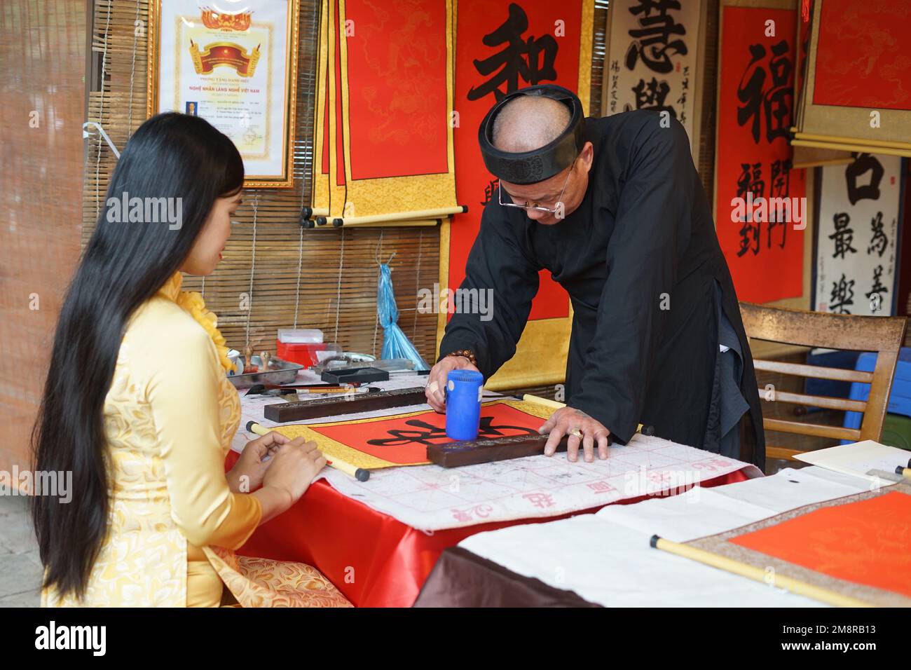 Hanoi, Vietnam. 15. Januar 2023. Ein Kalligraf erstellt kalligraphische Arbeiten für eine Frau während des Spring Calligraphy Festivals am Van Mieu-Quoc TU Giam (Literaturtempel) in Hanoi, Vietnam, 15. Januar 2023. Das jährliche Frühjahrskalligrafiefest fand am Sonntag in der vietnamesischen Hauptstadt Hanoi statt, nachdem die COVID-19-Pandemie zwei Jahre zurückliegt. Es ist eine lokale Tradition, kalligraphische Werke auf rotem Papier zu haben, die während des Mondneujahrs ausgestellt werden, um für das gute im neuen Jahr zu beten. Kredit: Hu Jiali/Xinhua/Alamy Live News Stockfoto