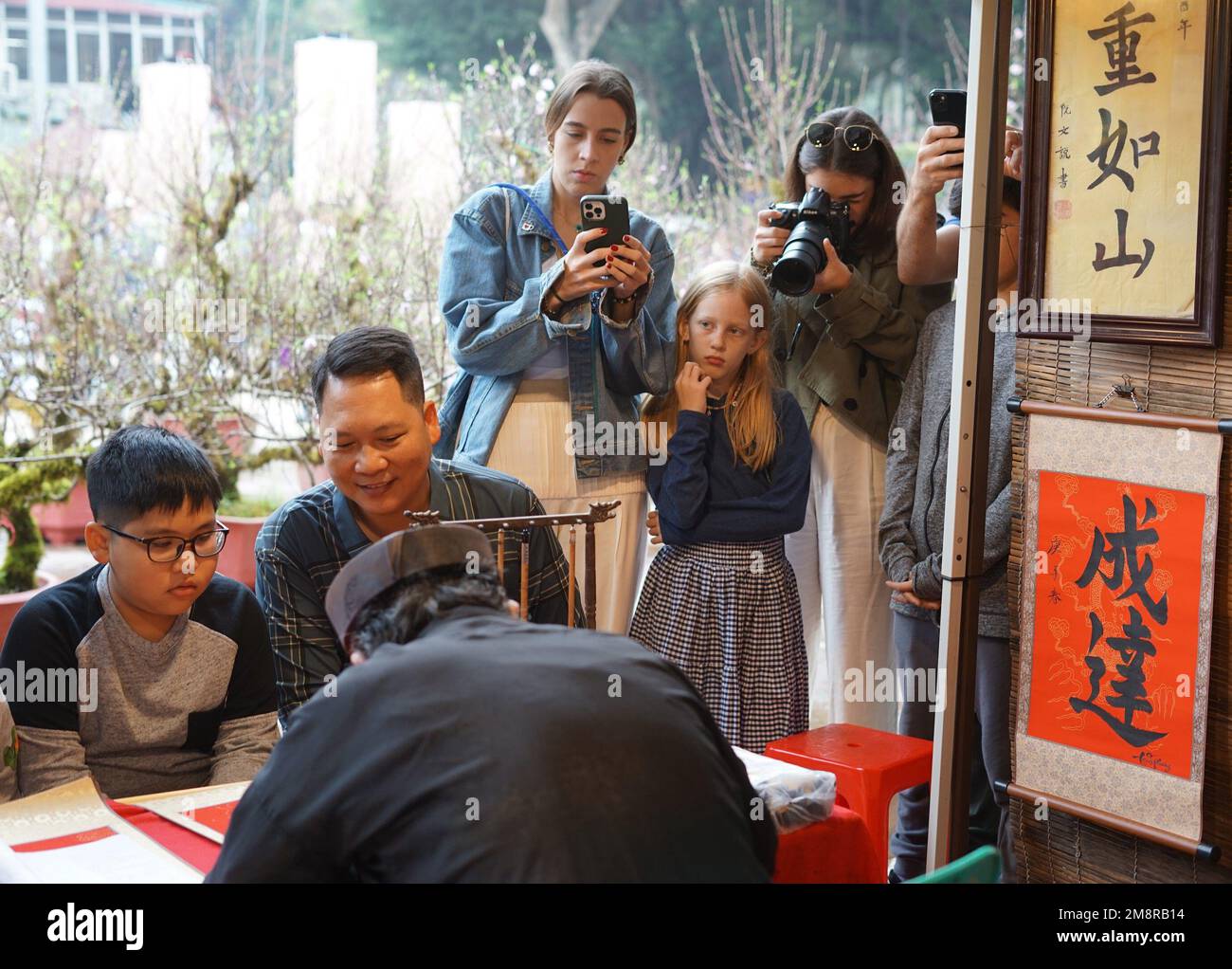 Hanoi, Vietnam. 15. Januar 2023. Während des Spring Calligraphy Festivals im Van Mieu-Quoc TU Giam (Literaturtempel) in Hanoi, Vietnam, am 15. Januar 2023 sehen die Menschen einen Kalligrafen, der Kalligraphie schreibt. Das jährliche Frühjahrskalligrafiefest fand am Sonntag in der vietnamesischen Hauptstadt Hanoi statt, nachdem die COVID-19-Pandemie zwei Jahre zurückliegt. Es ist eine lokale Tradition, kalligraphische Werke auf rotem Papier zu haben, die während des Mondneujahrs ausgestellt werden, um für das gute im neuen Jahr zu beten. Kredit: Hu Jiali/Xinhua/Alamy Live News Stockfoto
