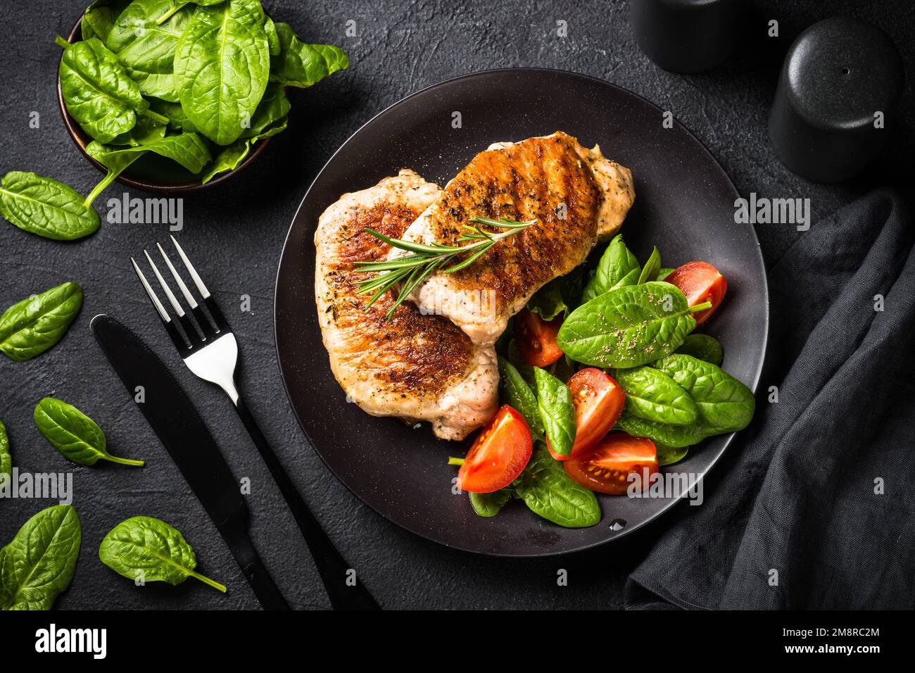 Gegrilltes Fleisch. Schweinesteaks mit frischem Salat. Draufsicht Bild am schwarzen Tisch. keto Diät Mittagessen. Stockfoto