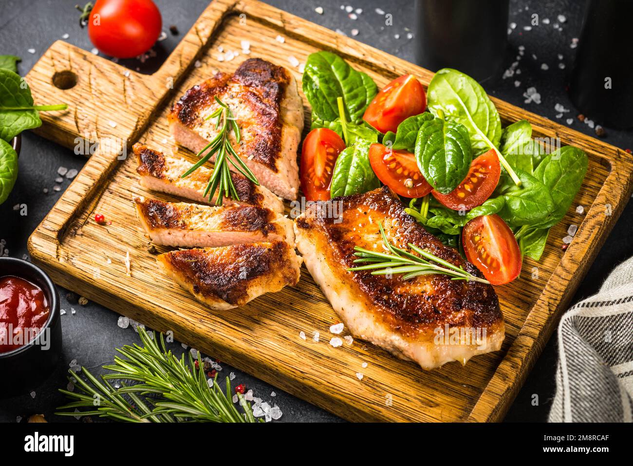 Fleischsteaks mit frischem Salat, serviert auf Holzbrettchen. Keto-Diät-Essen. Nahaufnahme Stockfoto