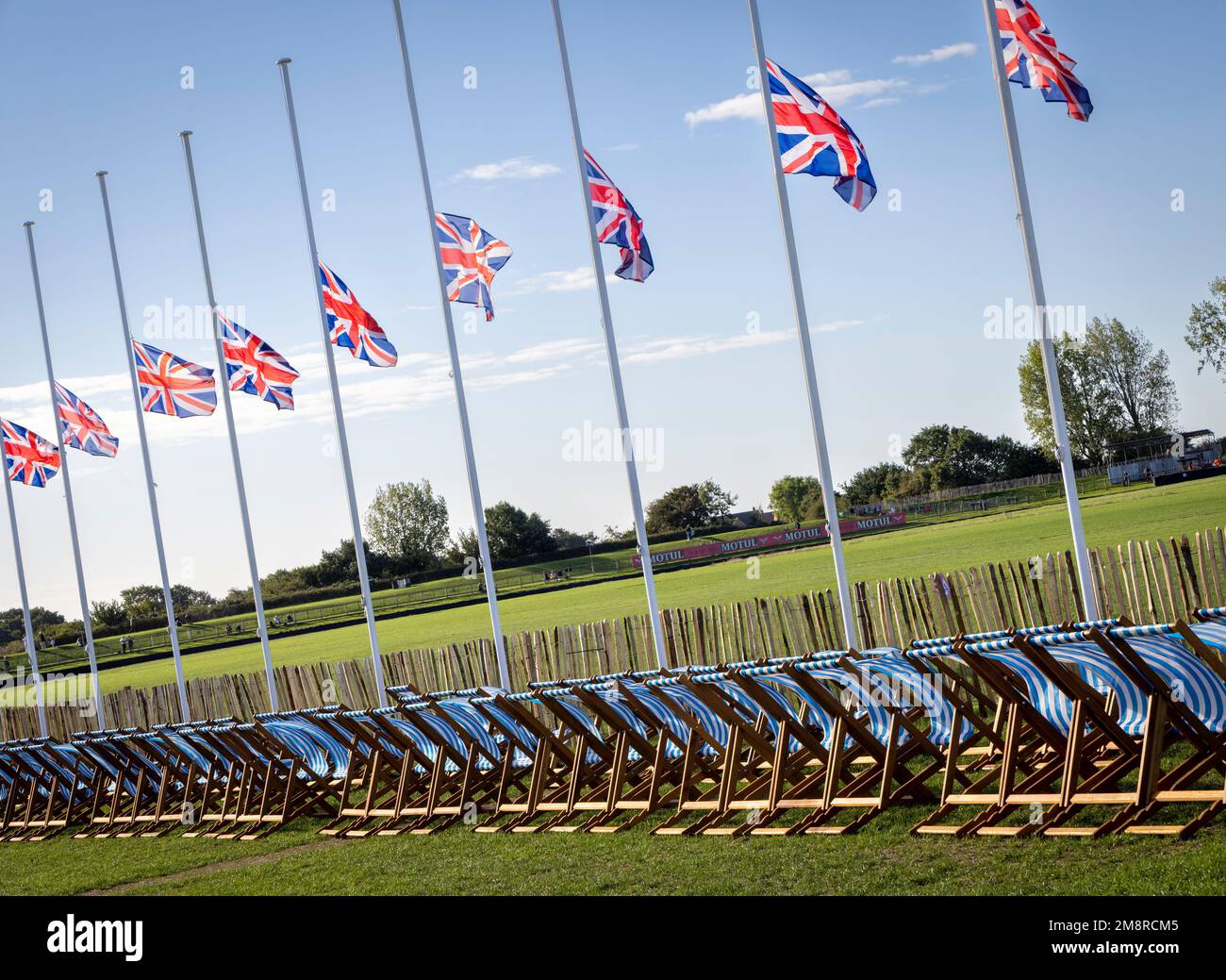 Leere Liegestühle und Flaggen am Halbmast zur Erinnerung an den Tod von Königin Elizabeth bei der 2022. Goodwood Revival, Sussex, Großbritannien. Stockfoto