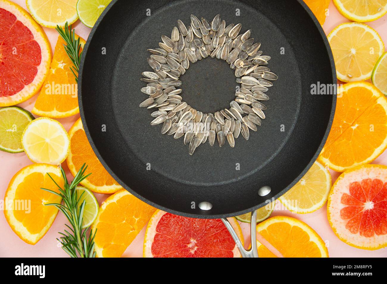 Hintergrund der Scheiben von Zitrusfrüchten, Orangen, Zitronen, Limetten, Grapefruits, Auf dem eine schwarze Pfanne platziert wird, in der eine Sonnenblume hergestellt wird Stockfoto