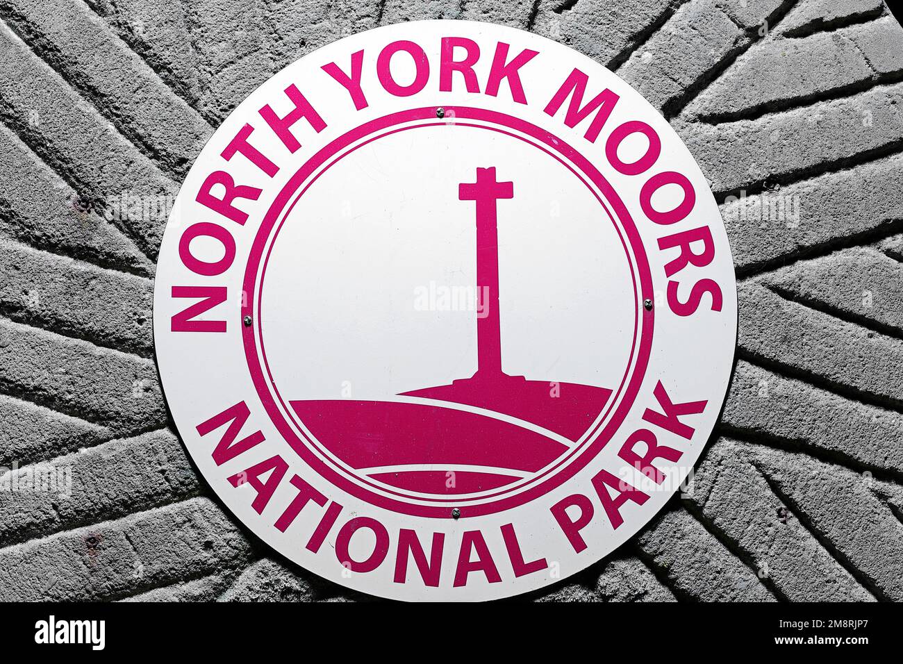 North York Moors National Park-Schild auf einem Mühlstein am Fuße der Sutton Bank in North Yorkshire, Großbritannien Stockfoto
