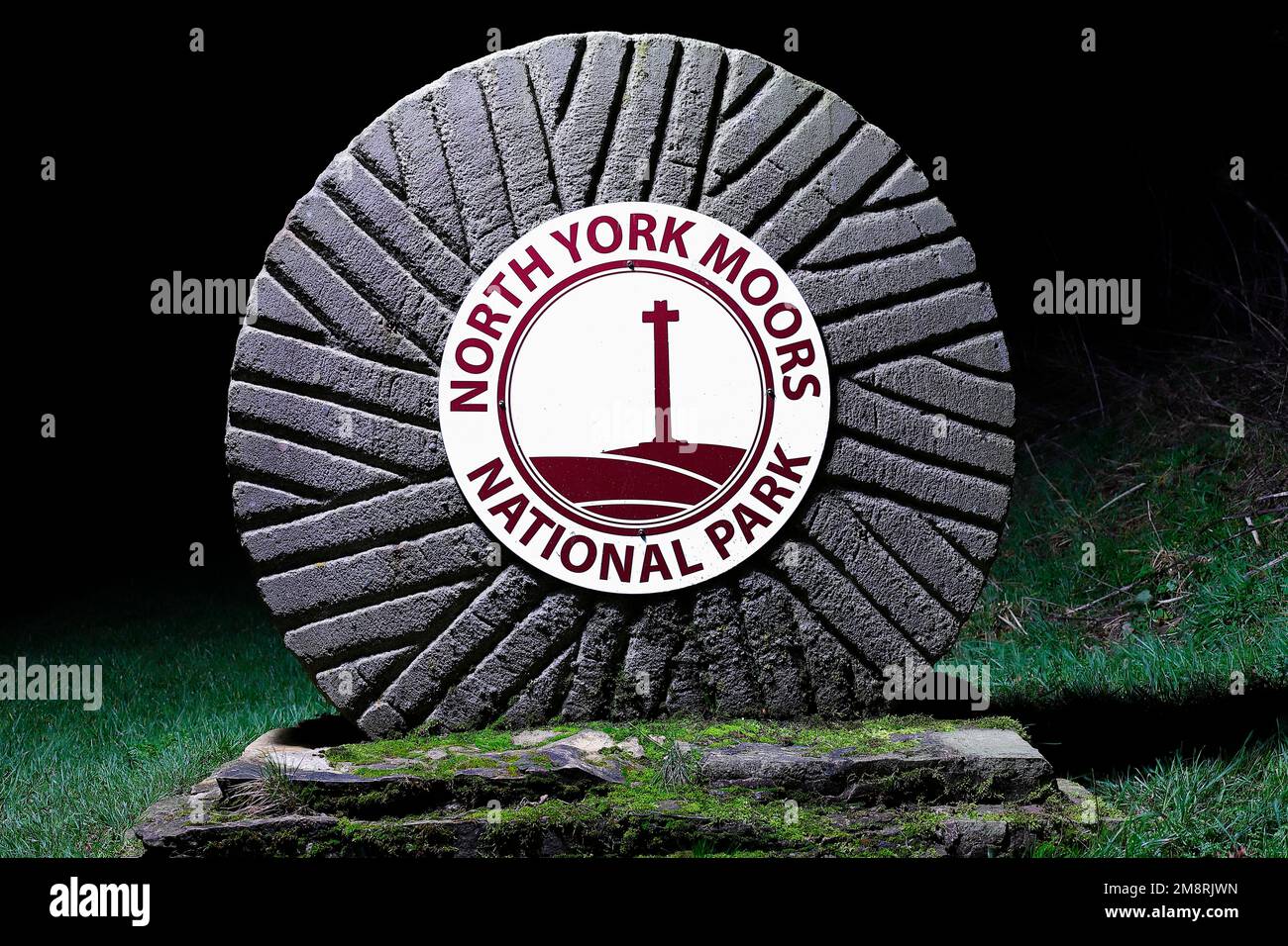 North York Moors National Park-Schild auf einem Mühlstein am Fuße der Sutton Bank in North Yorkshire, Großbritannien Stockfoto